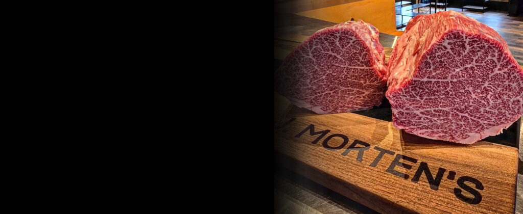 A close-up shot of a raw A5 Wagyu steak, highlighting its incredibly dense, intricate white marbling across the tender pink meat.