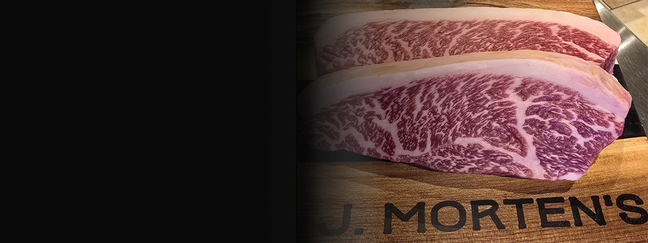 Hi-end steak on butcher block that says J Morten's/